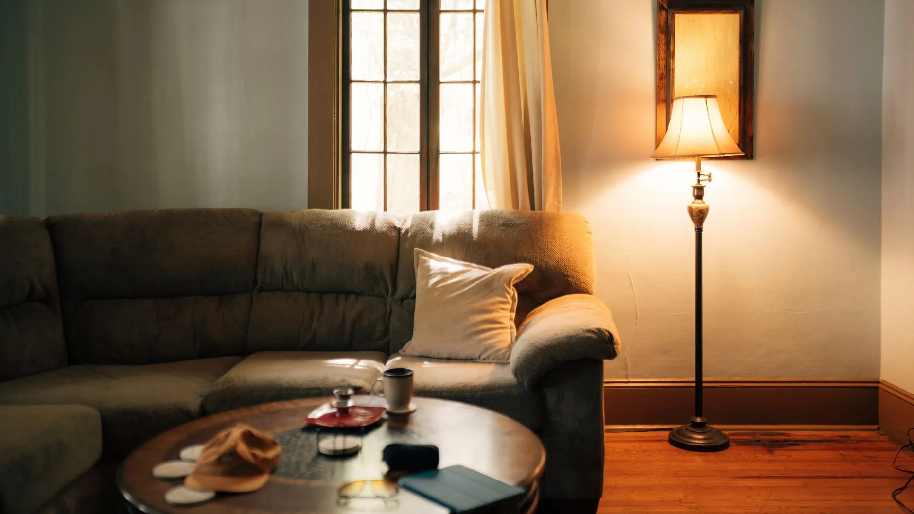 A sofa and a glowing floor lamp in a warm, quiet living room.