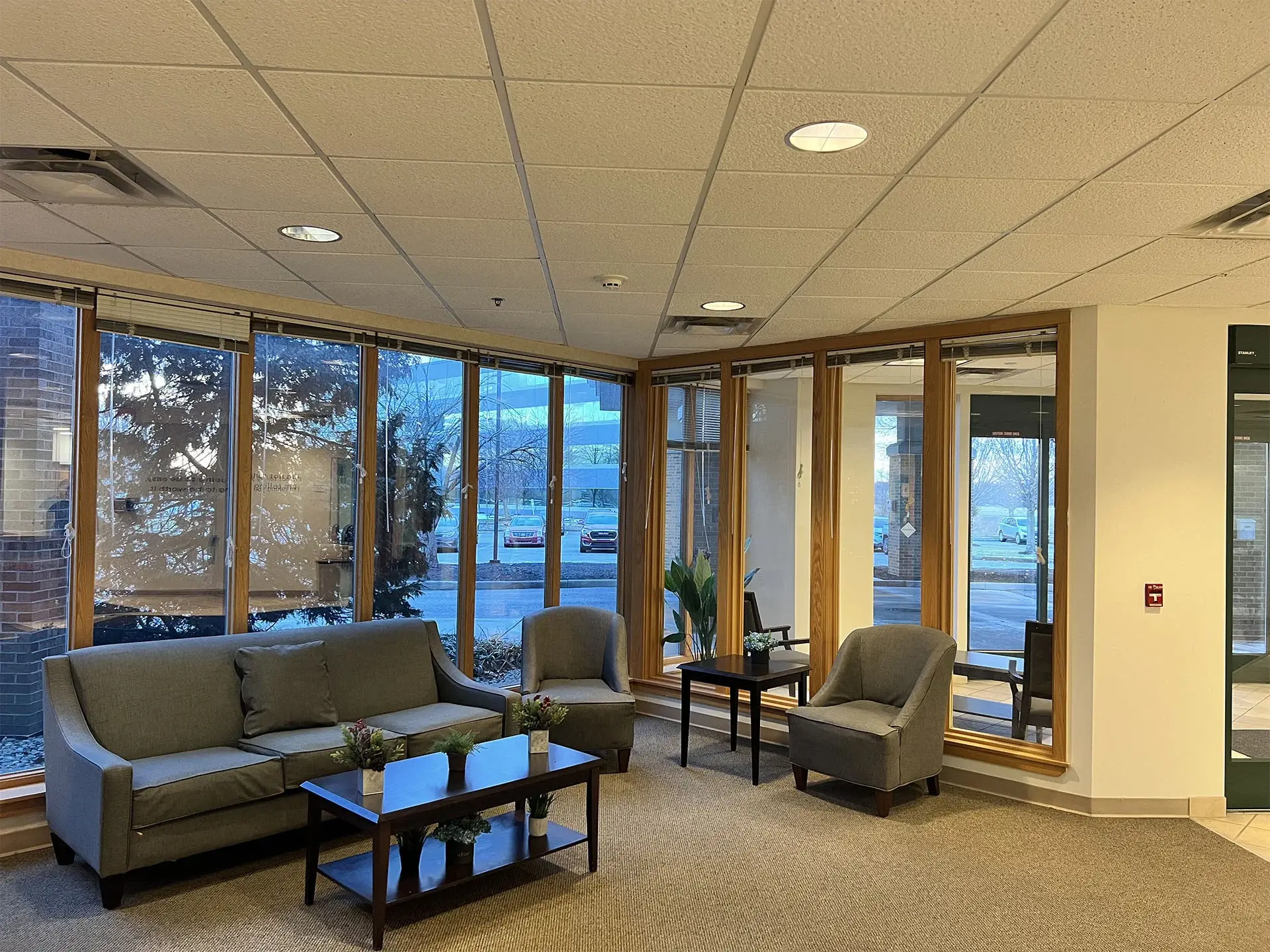 The waiting area at Jasper Grove Recovery — armchairs and a sofa beside floor-to-ceiling windows looking onto trees.
