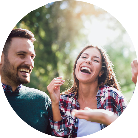 A young man and a young woman are sitting outside and laughing. They're enjoying life after addiction treatment at Jasper Grove Recovery.