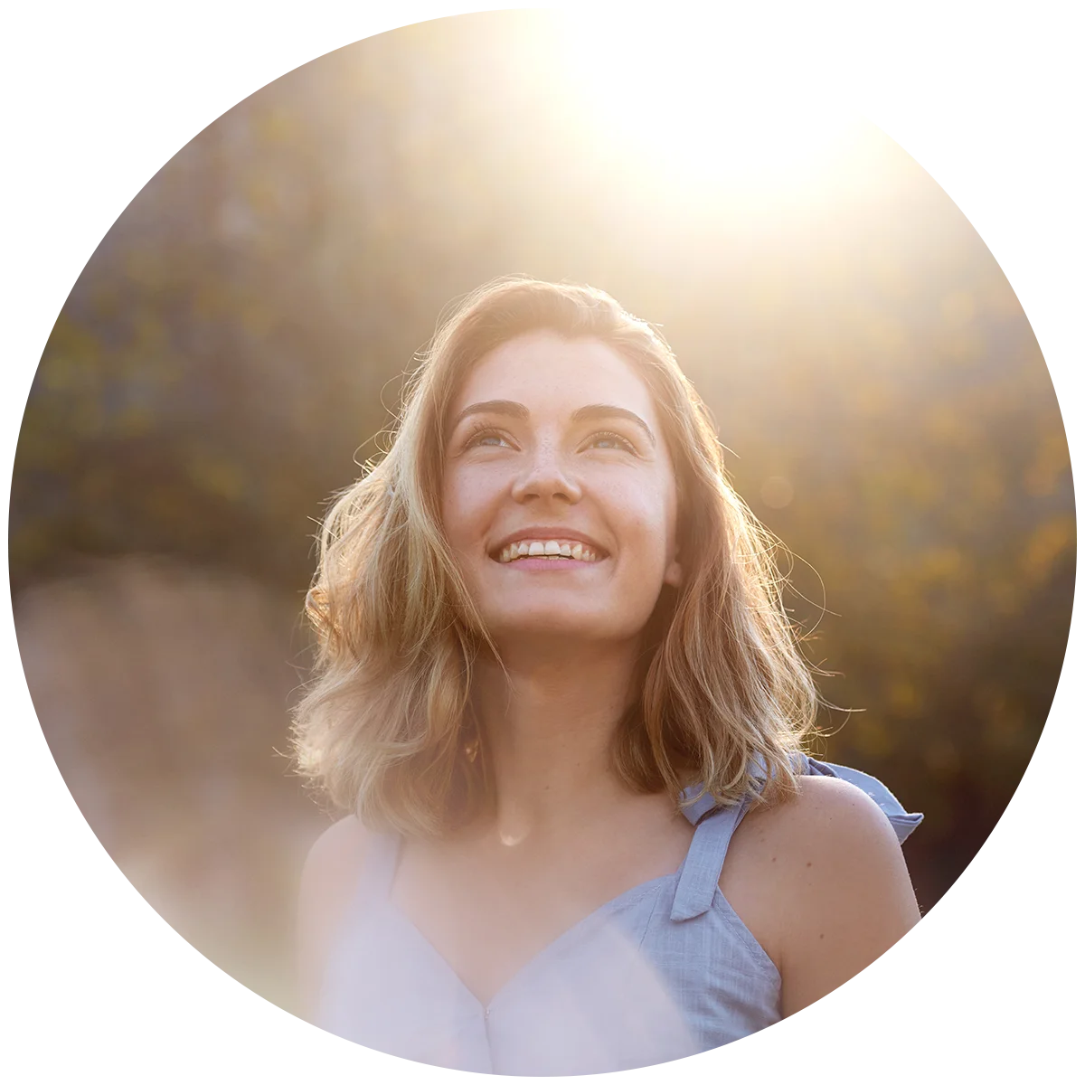A young woman stands outside at dusk, staring up at the sky with a smile on her face. She is enjoying life after addiction treatment at Jasper Grove Recovery.