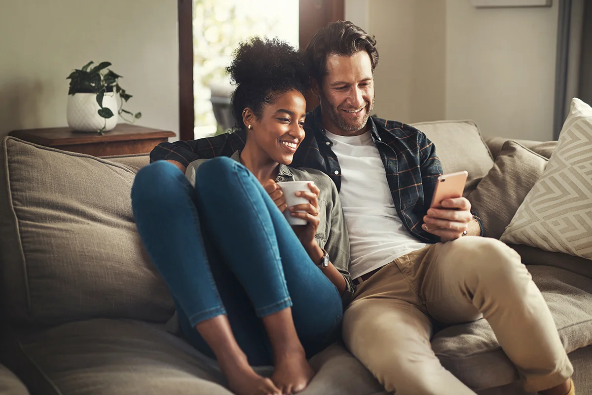 Two people on a couch looking at their phone